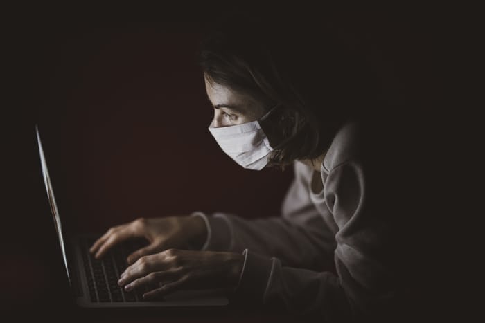 women doing copywriting on her laptop, with mask on