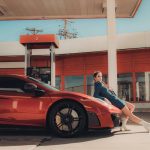 influencer marketing for a red car, model leaning on the car in front of a gas station